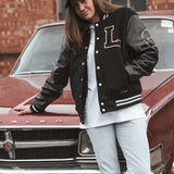 Black letterman jacket with wool body and leather sleeves. Paired with a black and white Legacy trucker cap.