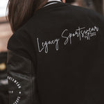 Legacy Sportswear written in white on back of black letterman jacket with wool body and leather sleeves.