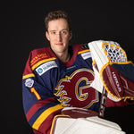 Person wearing a hockey jersey with a glove and stick, on a black background