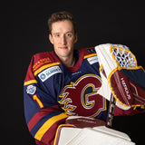 Person wearing a hockey jersey with a glove and stick, on a black background