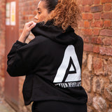 Back view of women's black oversized crop hoodie with tie waist and white Better Never Stops logo.