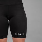 Women's black bike shorts with small white Legacy logo on the leg.