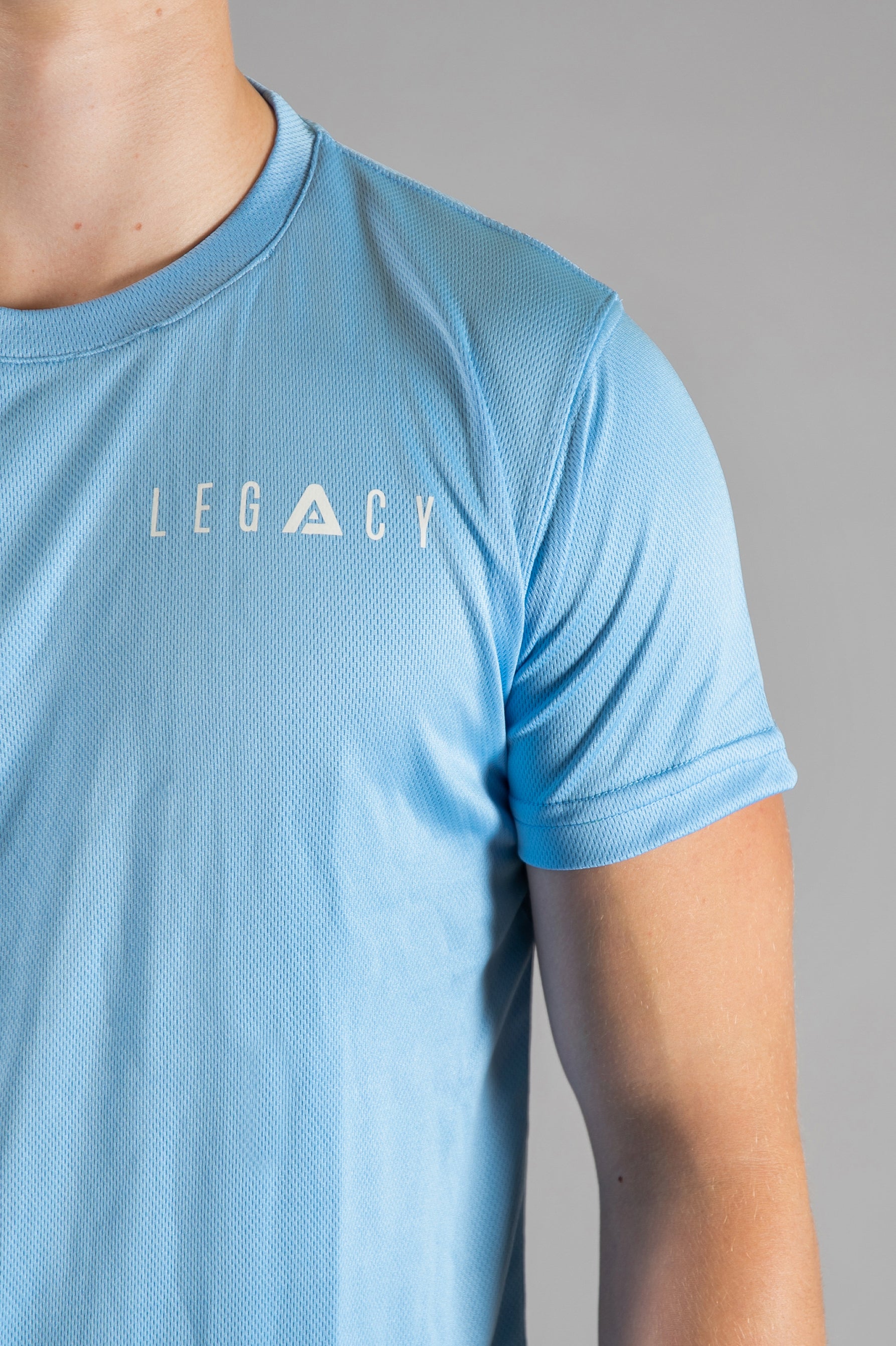 Close up of white logo on men's sky blue moisture wicking crewneck t-shirt.