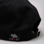 Close up of black Legacy x Lucky Seven baseball cap tag.