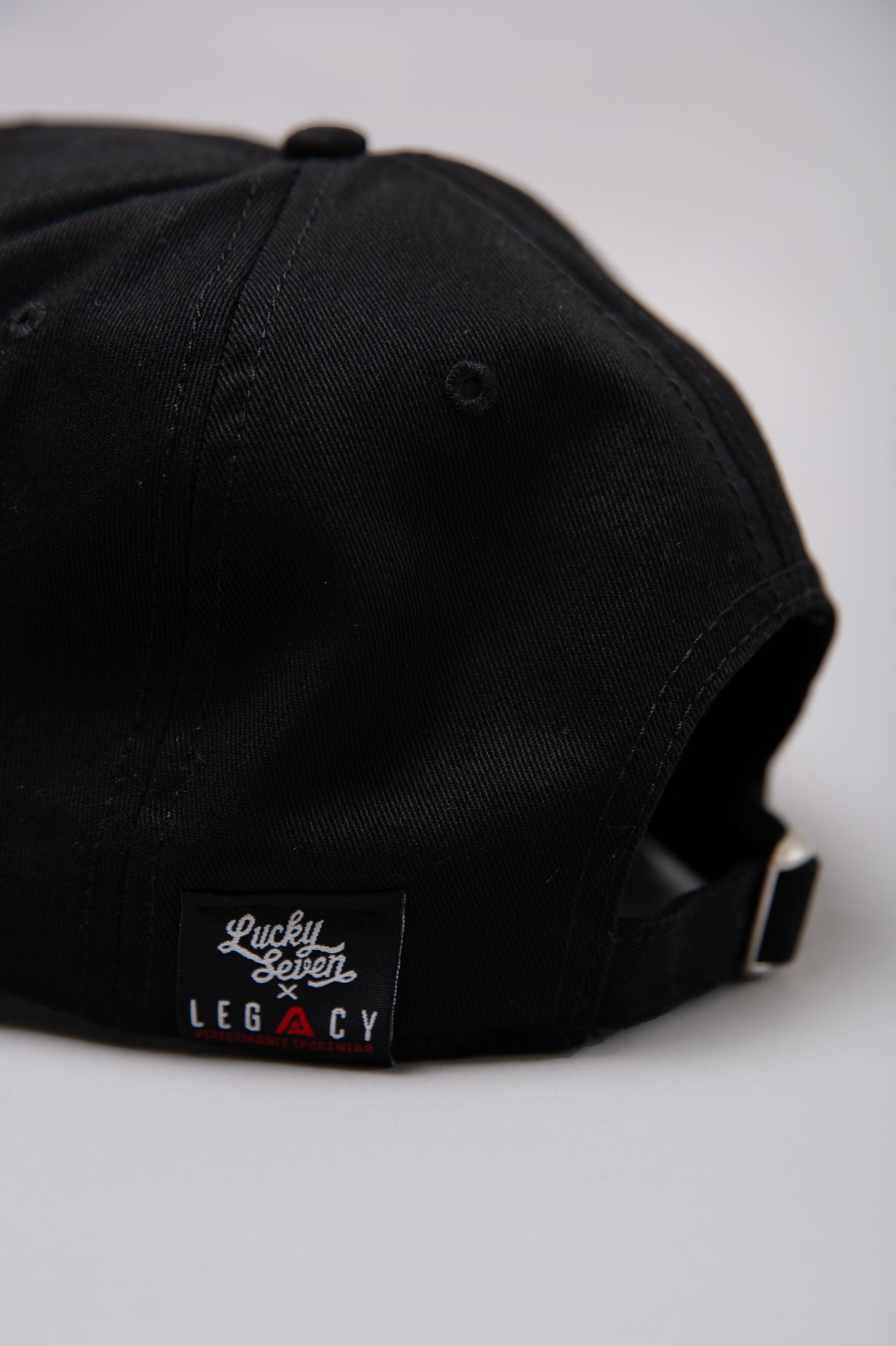 Close up of black Legacy x Lucky Seven baseball cap tag.