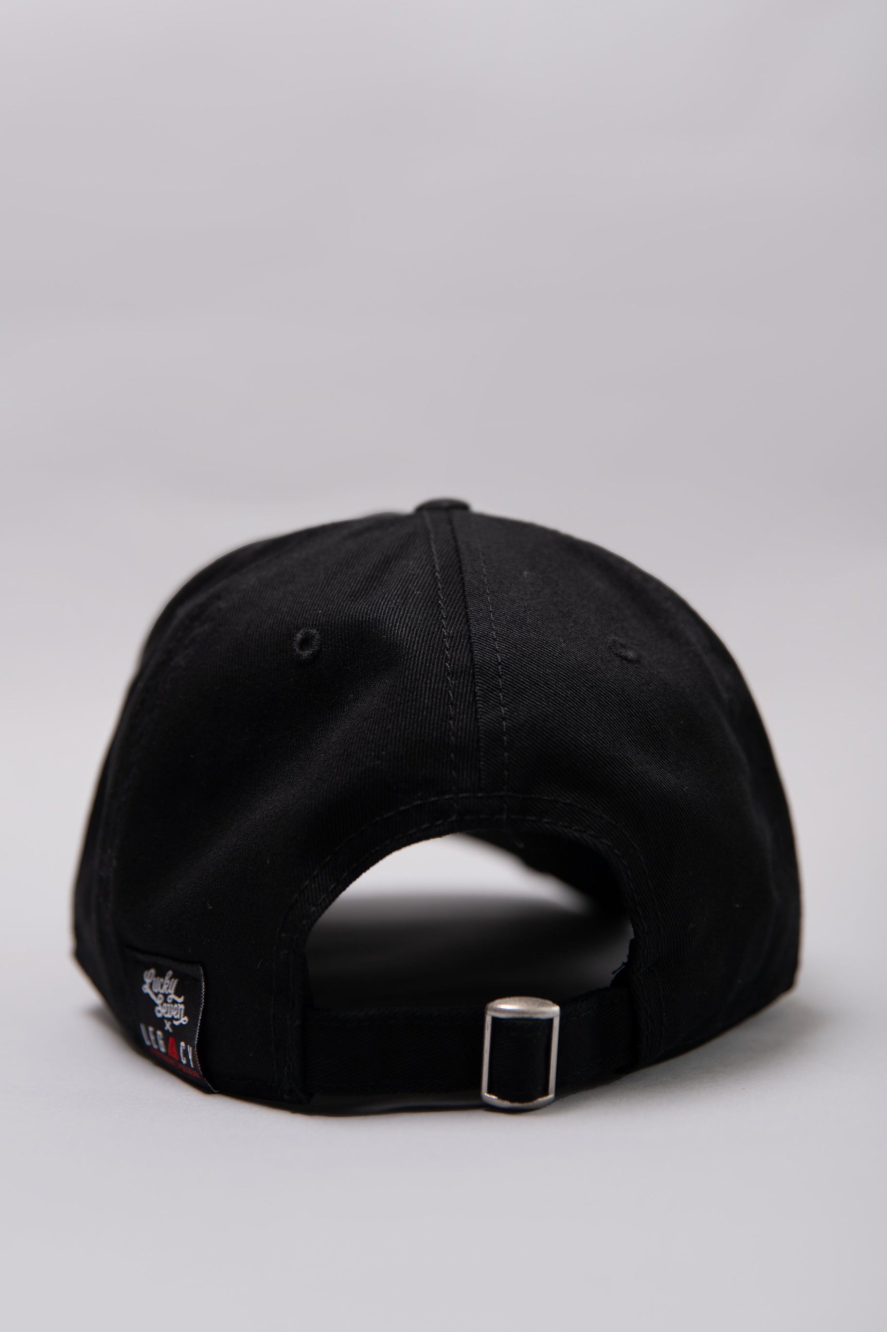 Snapback closure on black Legacy baseball cap with white and red logo. 