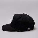 Side view of black Legacy baseball cap with white and red logo. 