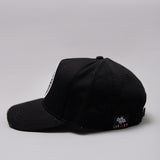 Side view of black Legacy baseball cap with white and red logo. 