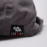 Close up of Lucky Seven x Legacy tag on grey baseball cap.