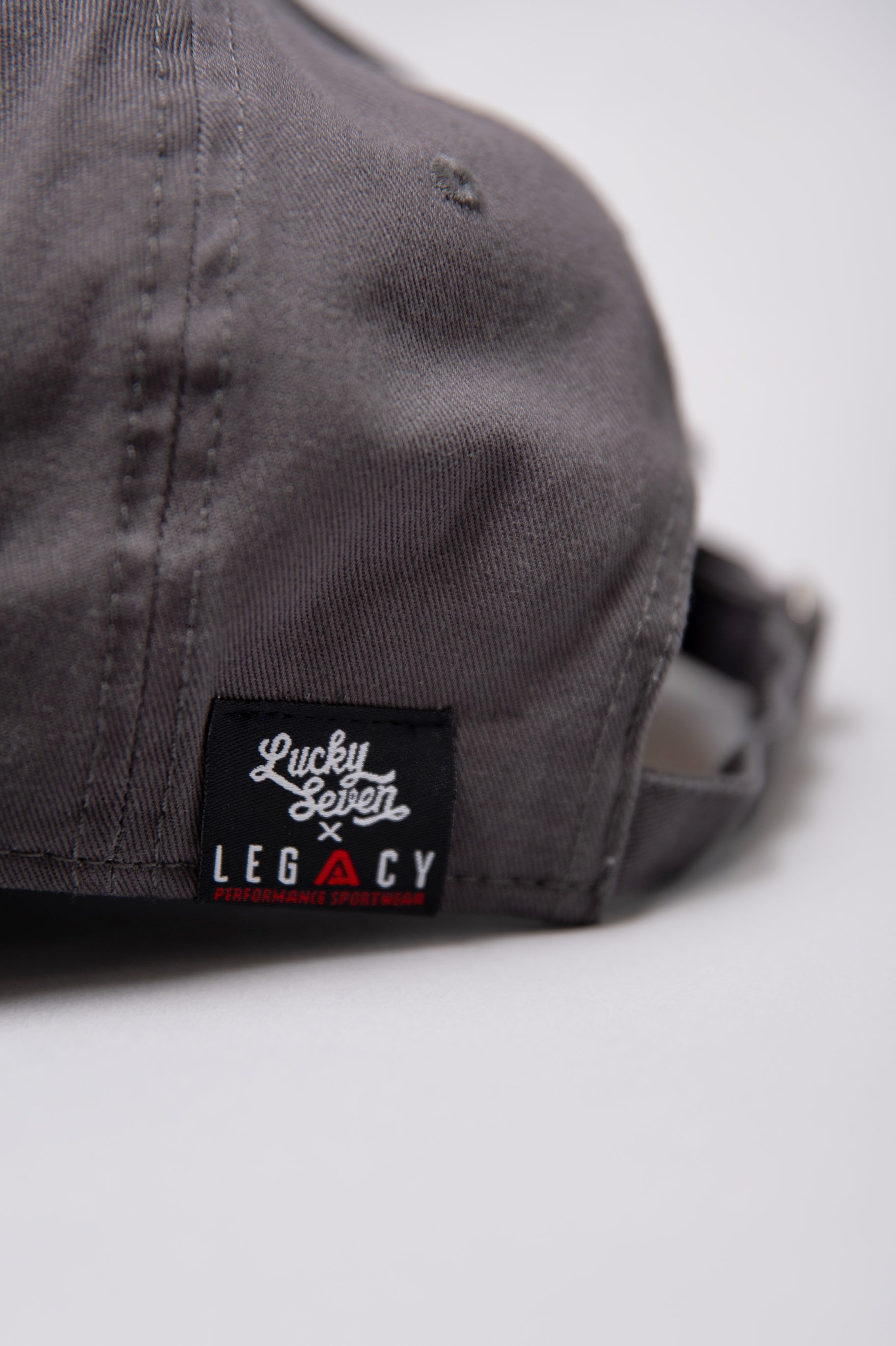 Close up of Lucky Seven x Legacy tag on grey baseball cap.