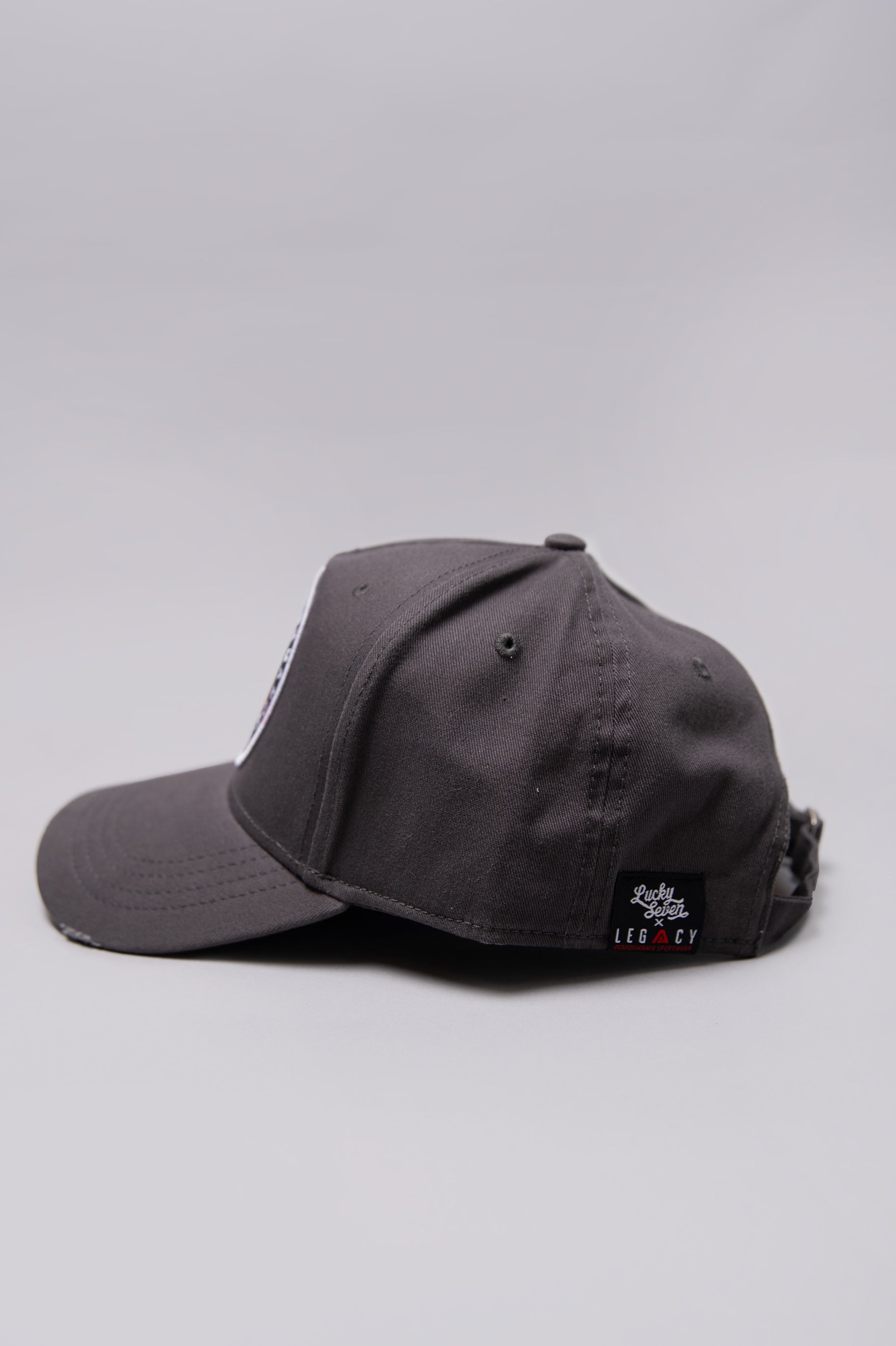 Side view of grey Legacy baseball cap with white, red and black logo.