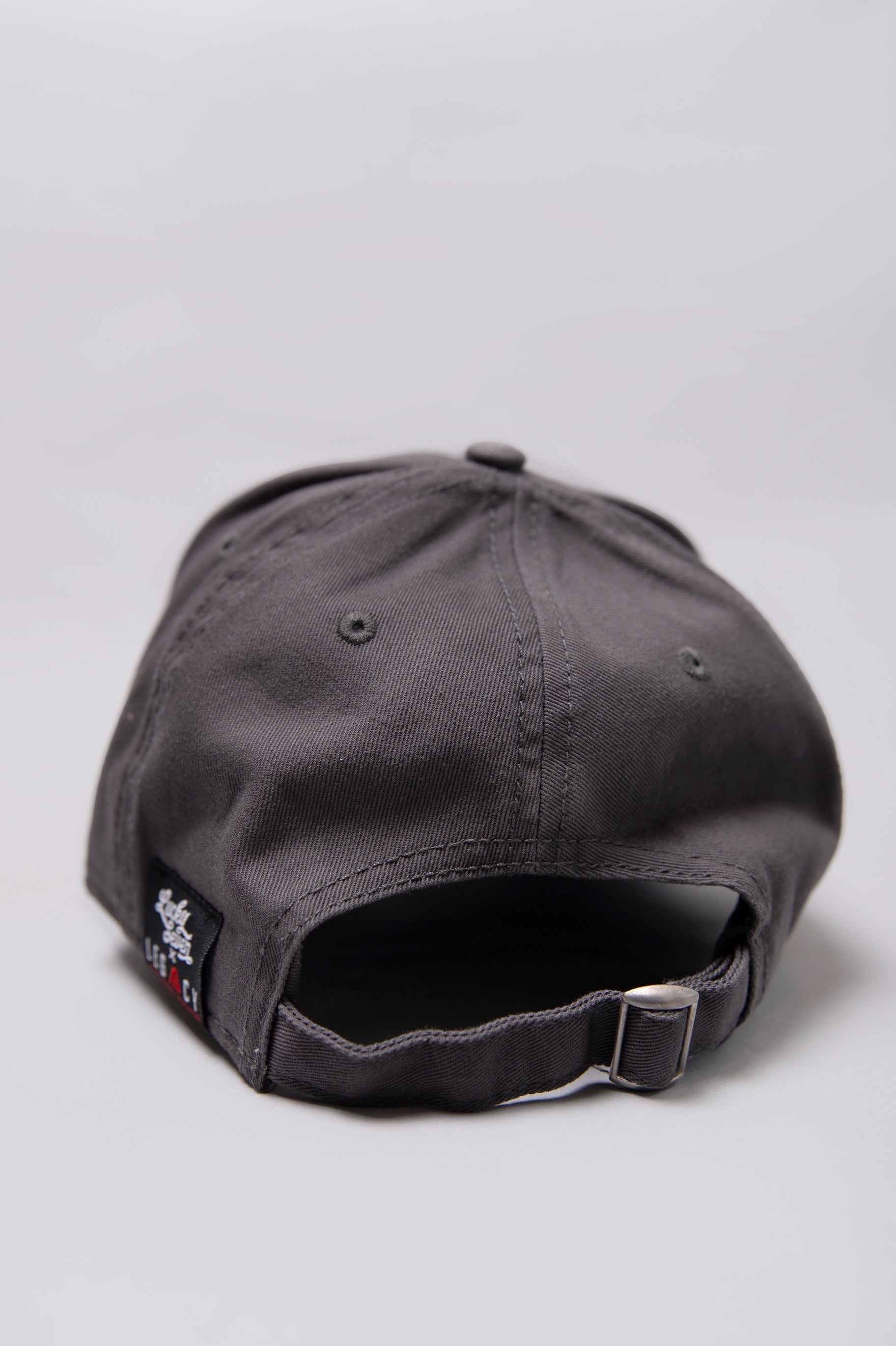 Snapback closure on grey Legacy baseball cap with white, red and black logo.