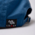 Close up of Legacy x Lucky Seven tag on navy baseball cap.