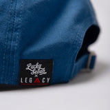 Close up of Legacy x Lucky Seven tag on navy baseball cap.