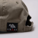 Close up of Legacy x Lucky Seven tag on khaki baseball cap.