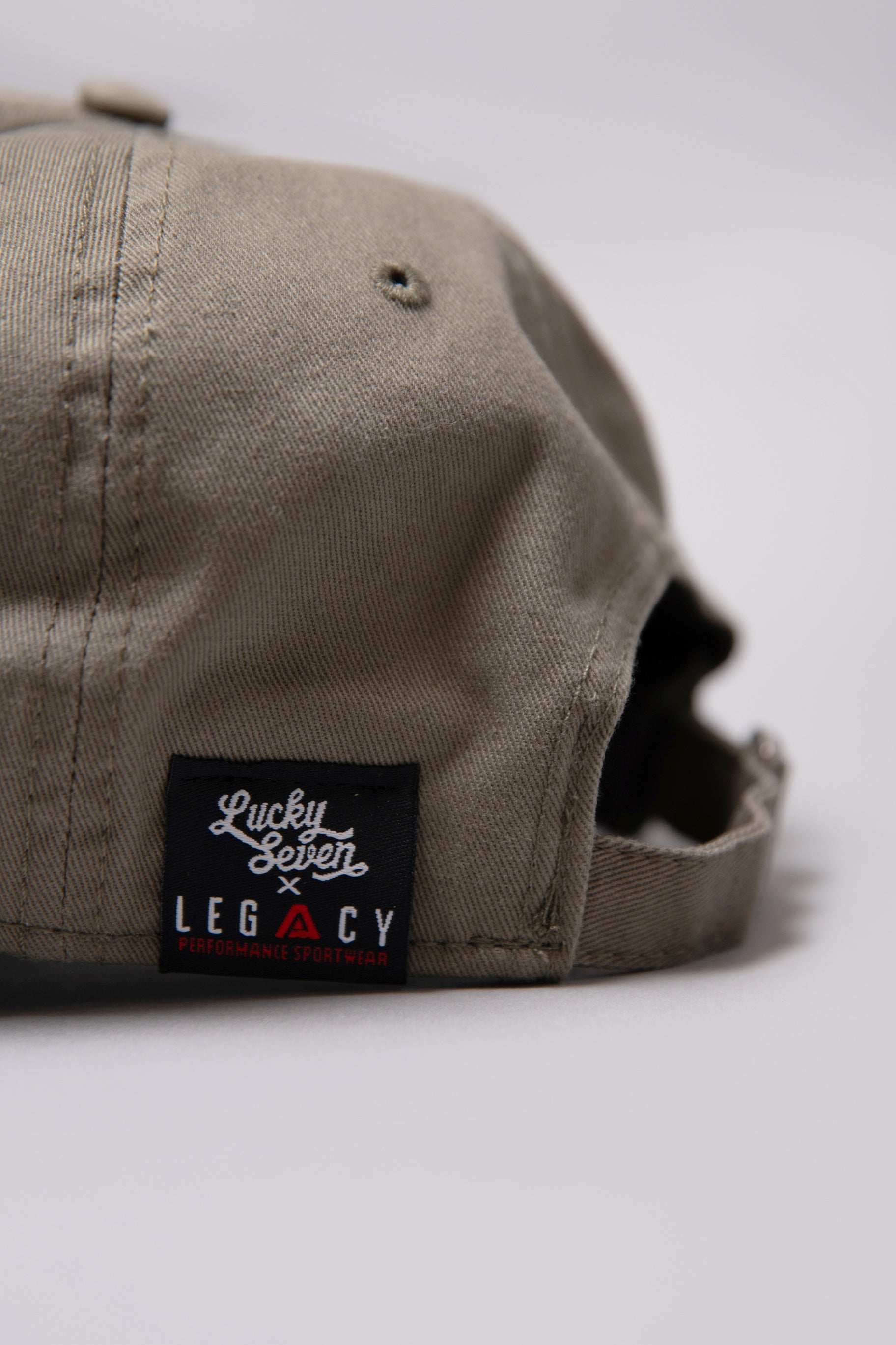 Close up of Legacy x Lucky Seven tag on khaki baseball cap.