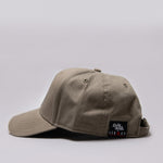 Side view of khaki Legacy baseball cap with black and white logo.