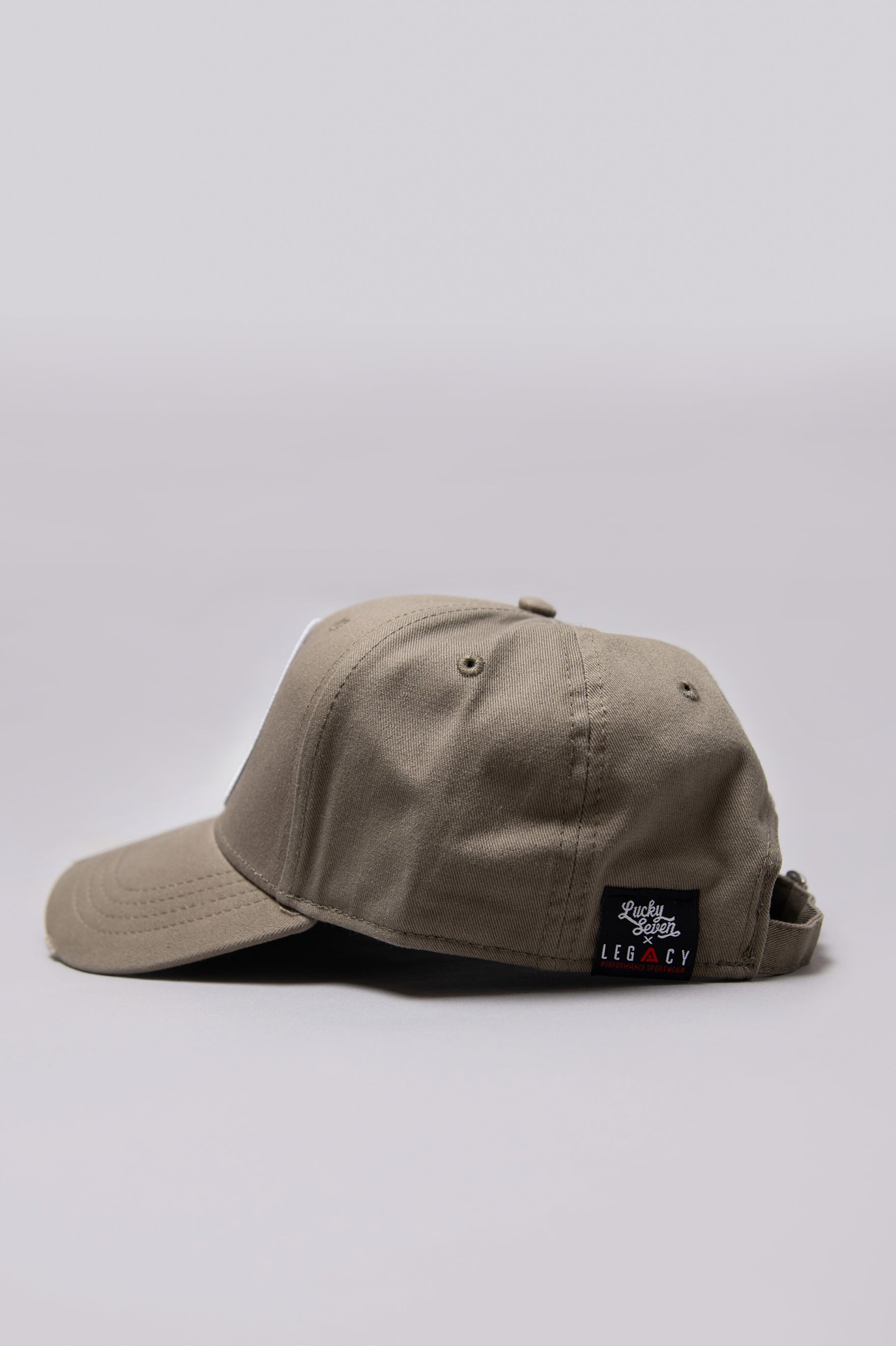 Side view of khaki Legacy baseball cap with black and white logo.