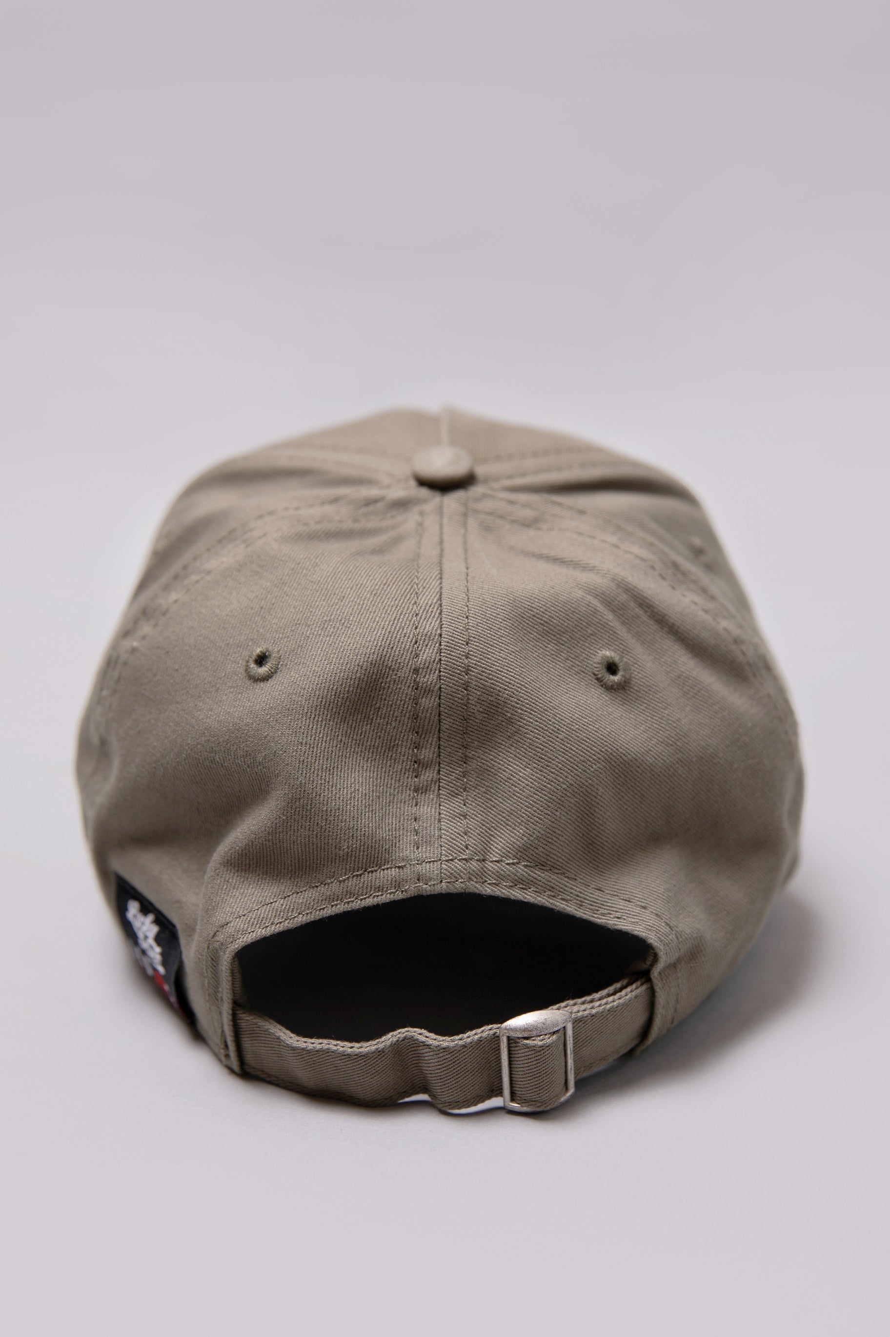 Snapback closure on khaki Legacy baseball cap with black and white logo.