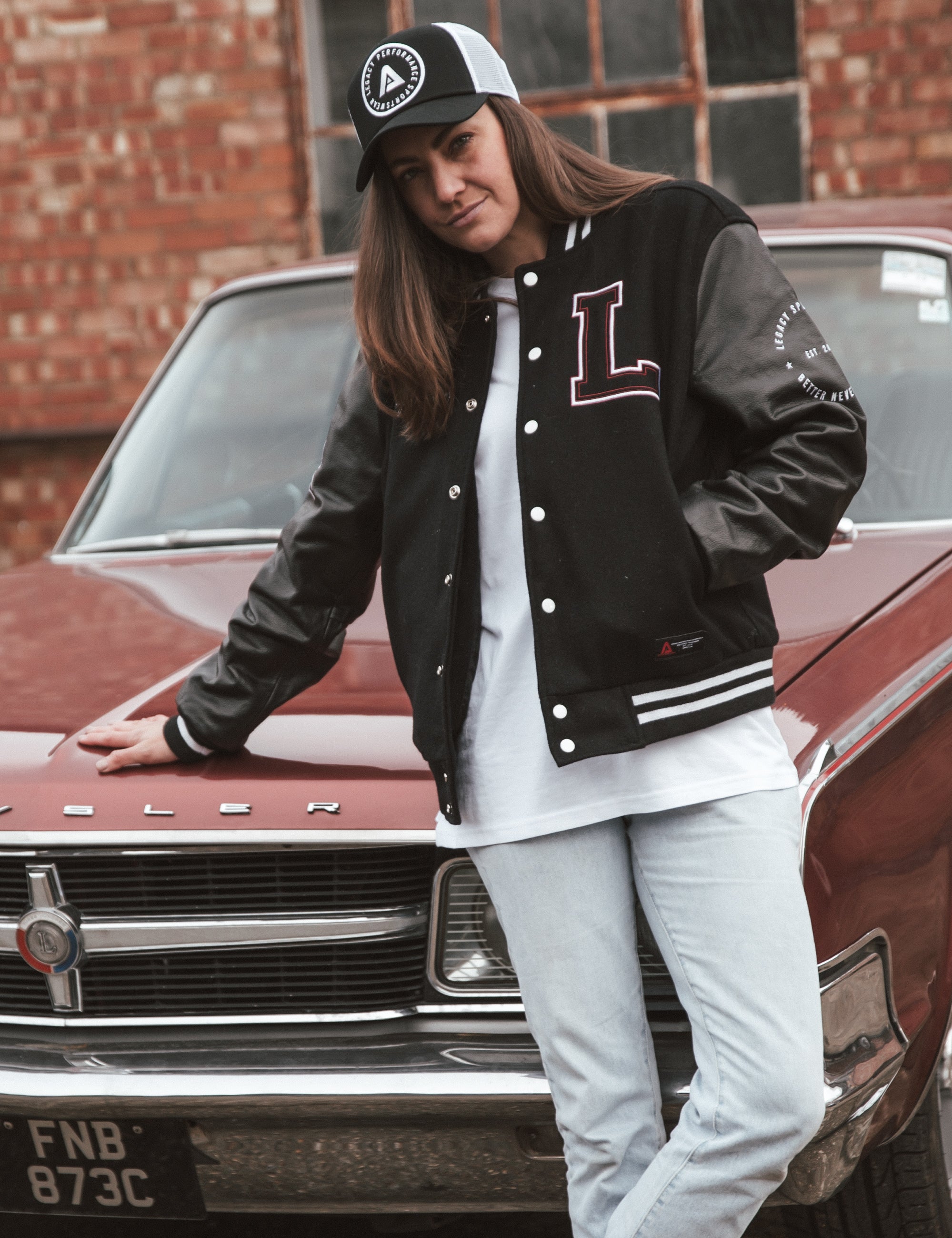 Black letterman jacket with wool body and leather sleeves. Paired with a black and white Legacy trucker cap.