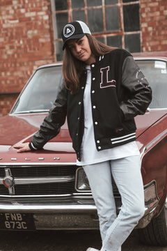 Black letterman jacket with wool body and leather sleeves. Paired with a black and white Legacy trucker cap.