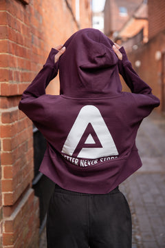 Back view of women's burgundy cropped hoodie with white Better Never Stops logo.