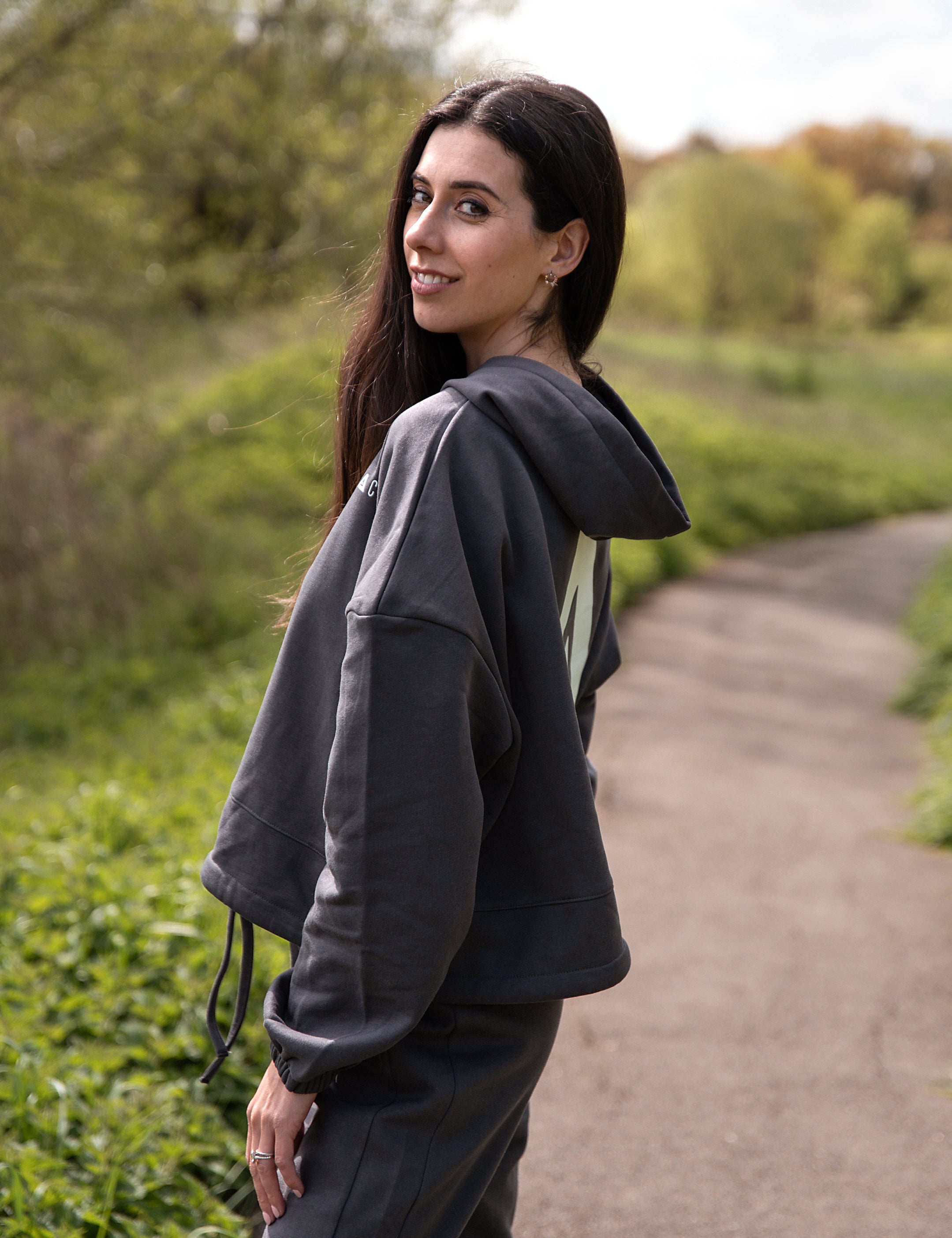 Women's graphite oversized crop hoodie with tie waist and white Better Never Stops logo on back.