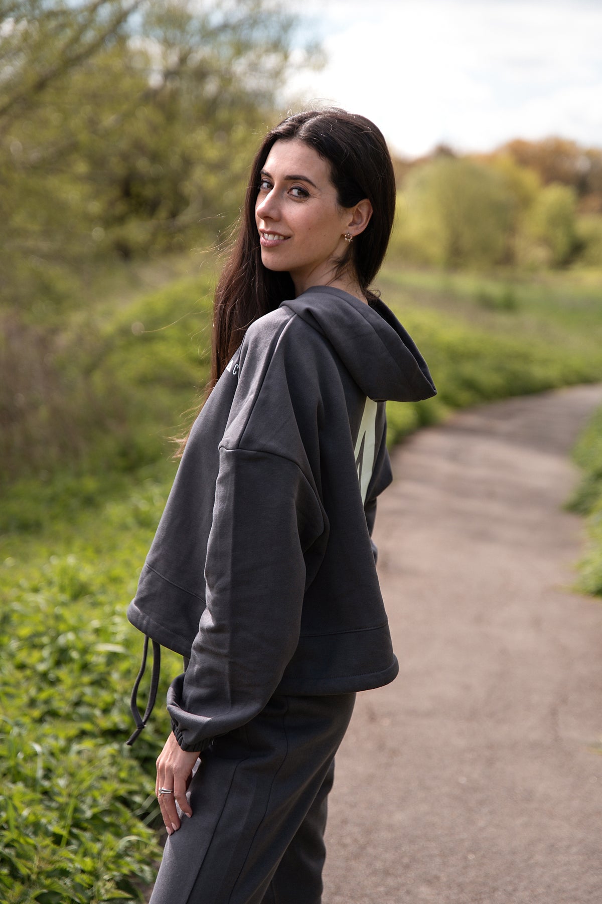 Women's graphite oversized crop hoodie with tie waist and white Better Never Stops logo on back.