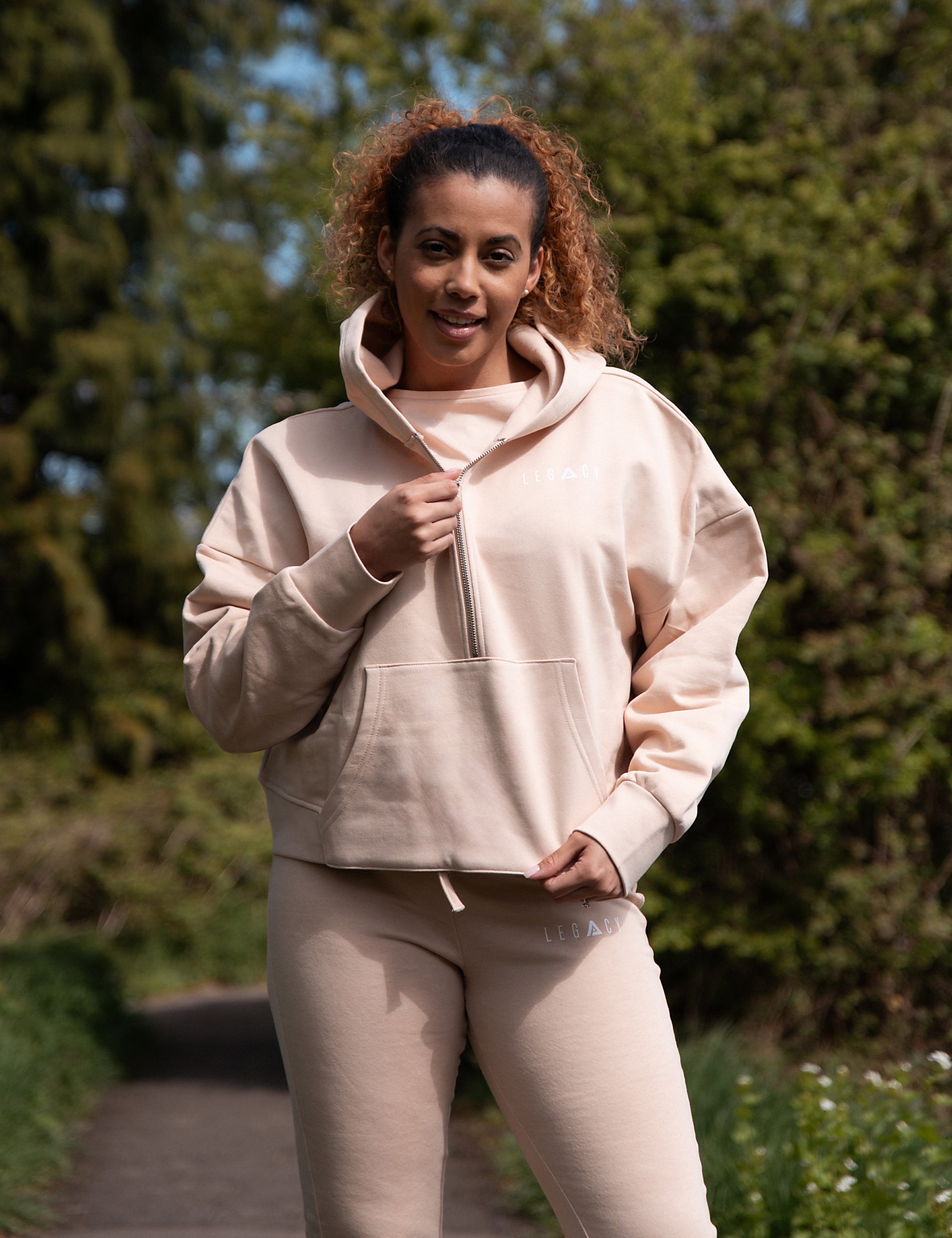 Women's soft pink 1/4 zip cropped hoodie with small white logo.