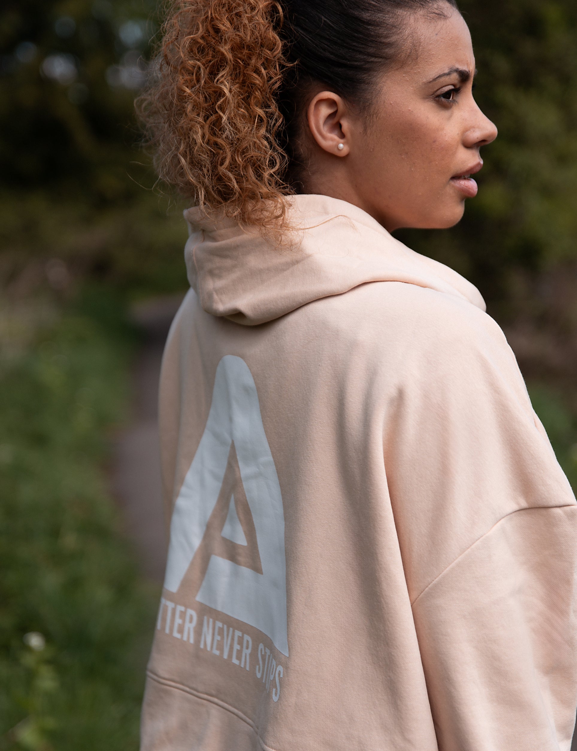 Back view of women's soft pink cropped hoodie with white Better Never Stops logo.