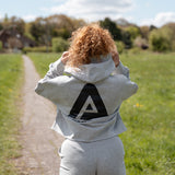 Back view of women's grey oversized crop hoodie with tie waist and black Better Never Stops logo.