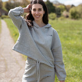 Women's grey oversized crop hoodie with tie waist and small black logo.
