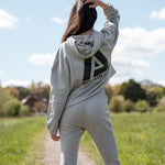 Back view of women's grey oversized crop hoodie with tie waist and black Better Never Stops logo.