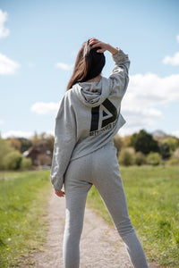 Back view of women's grey oversized crop hoodie with tie waist and black Better Never Stops logo.