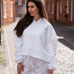Women's white oversized crop hoodie with tie waist and small black logo.