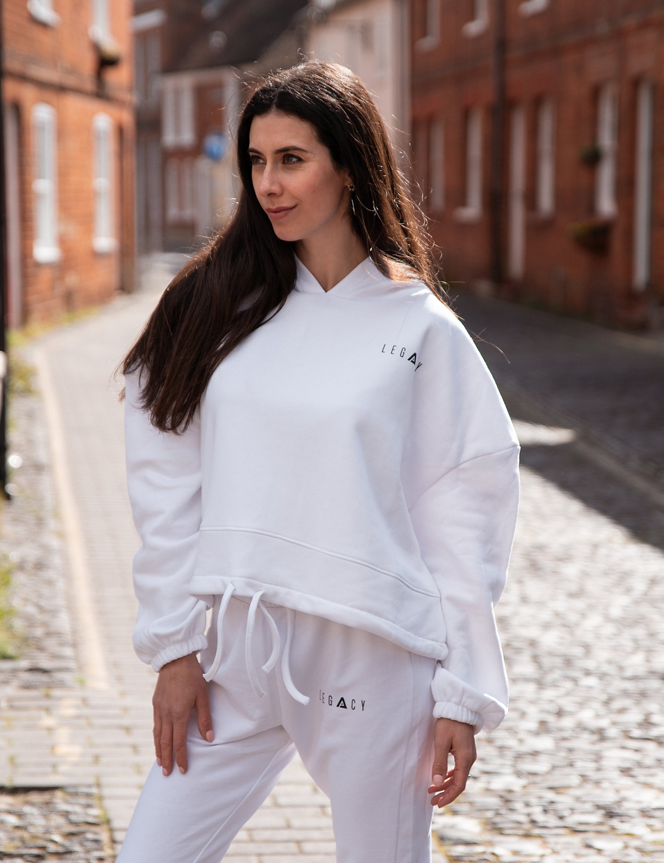 Women's white oversized crop hoodie with tie waist and small black logo.