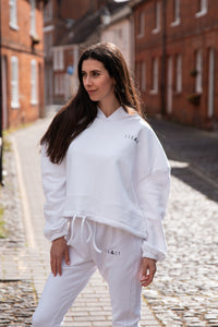 Women's white oversized crop hoodie with tie waist and small black logo.