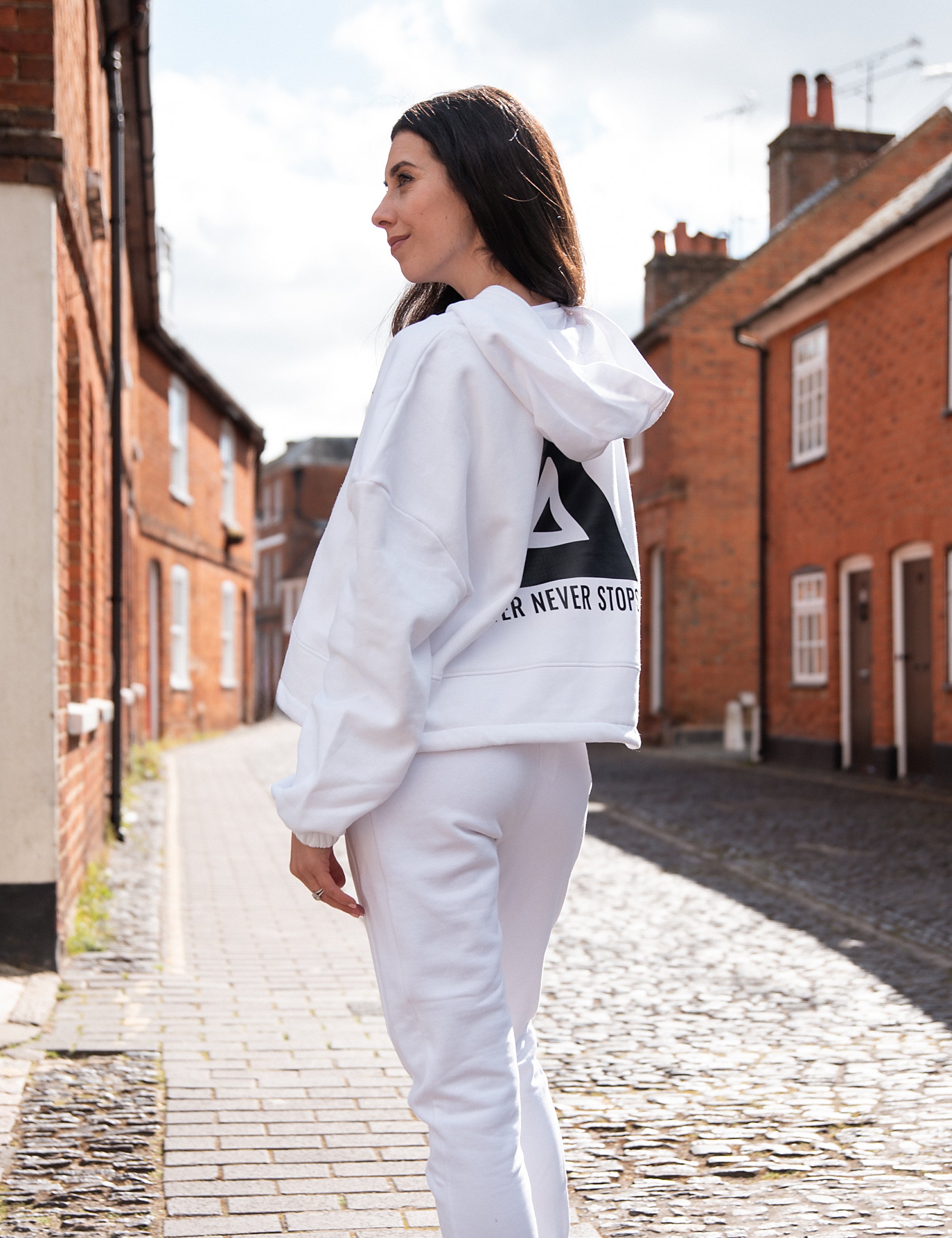 Back view of women's white oversized crop hoodie with tie waist and black Better Never Stops logo.
