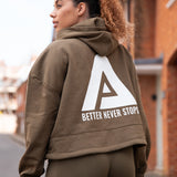 Back view of women's olive oversized crop hoodie with tie waist and white Better Never Stops logo.