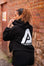 Back view of women's black oversized crop hoodie with tie waist and white Better Never Stops logo.