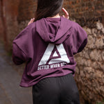 Back view of women's burgundy oversized crop hoodie with tie waist and white Better Never Stops logo.