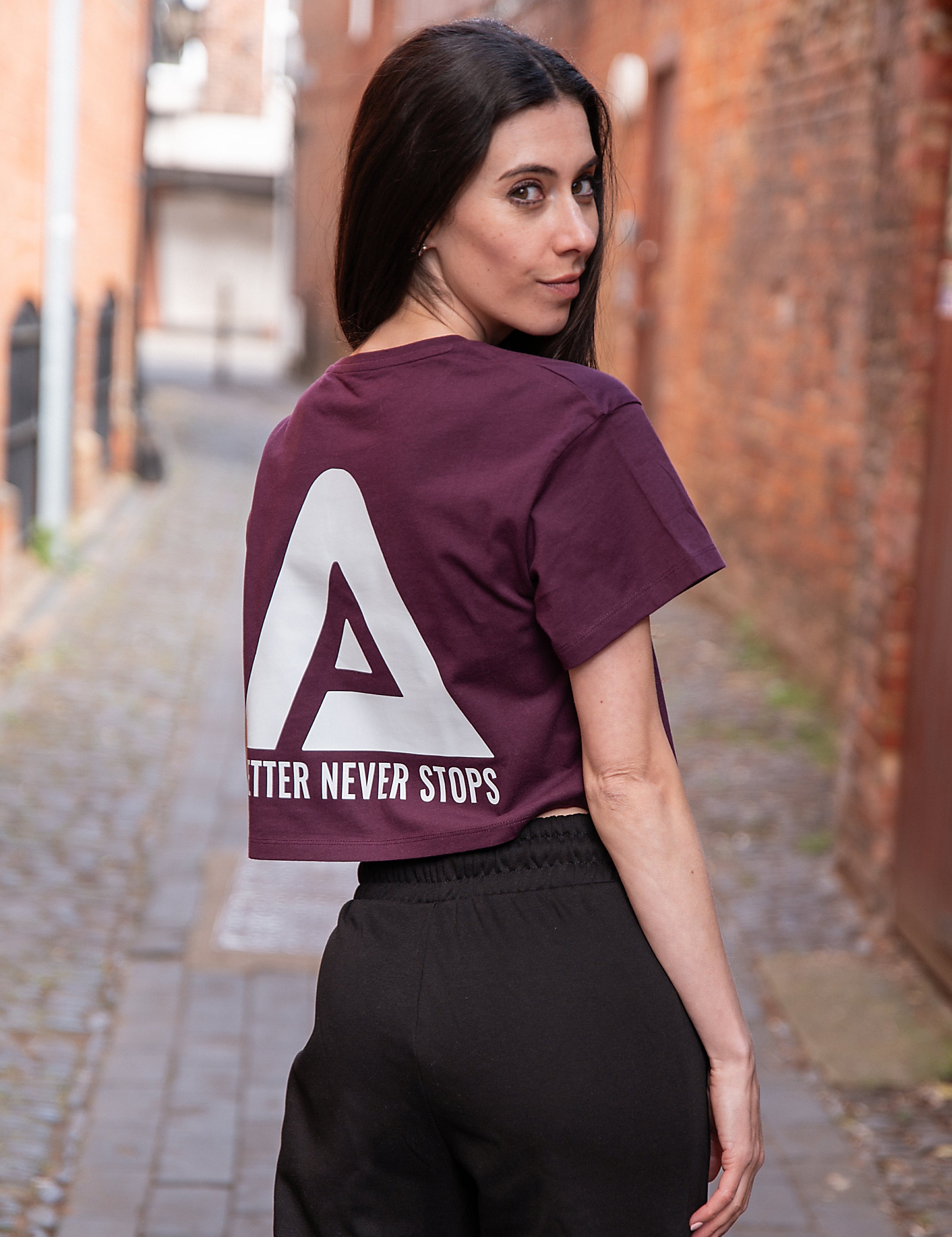Back view of women's burgundy crop t-shirt with white Better Never Stops logo.