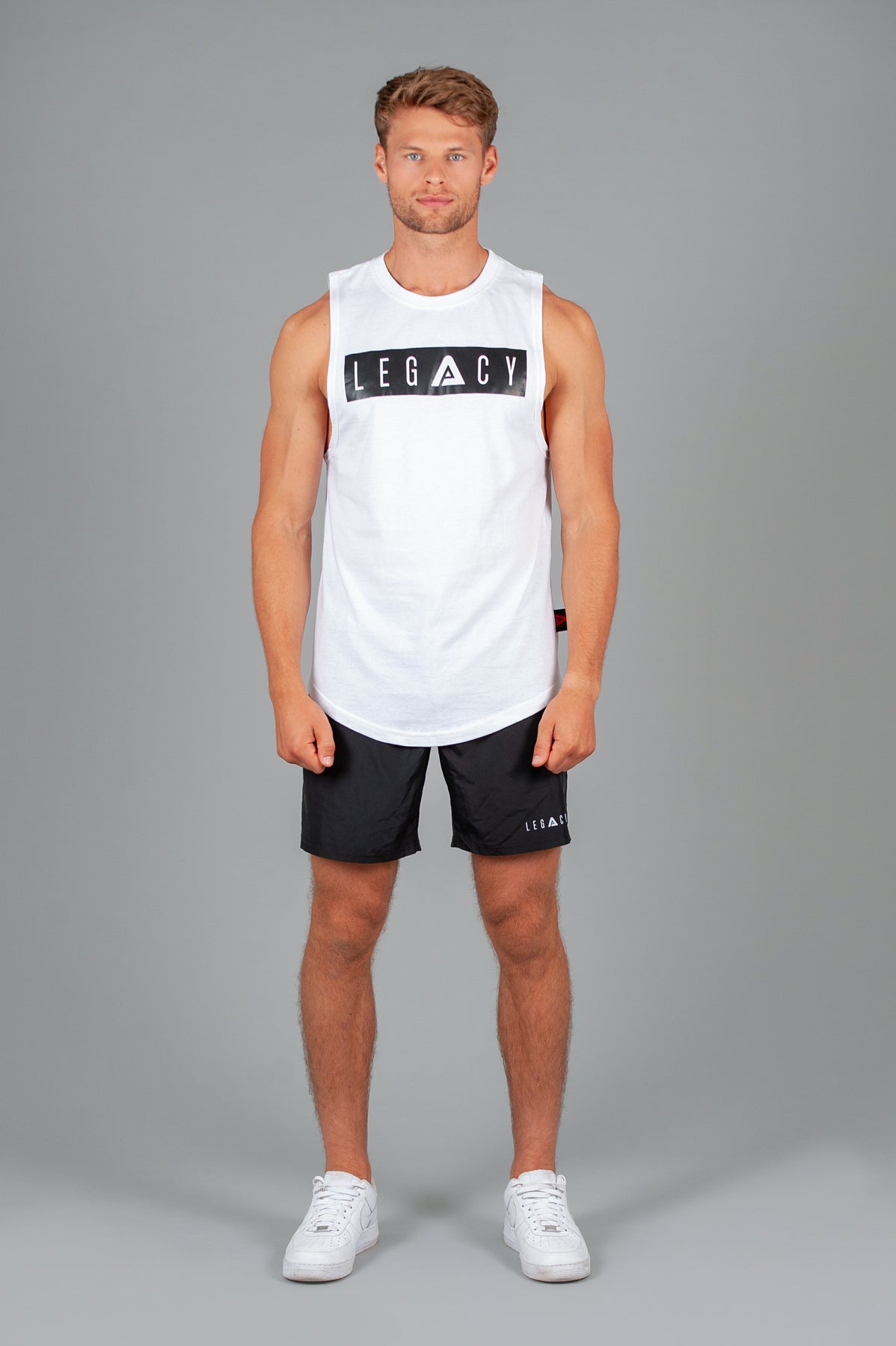 Men's white tank with black boxed Legacy logo across chest. 