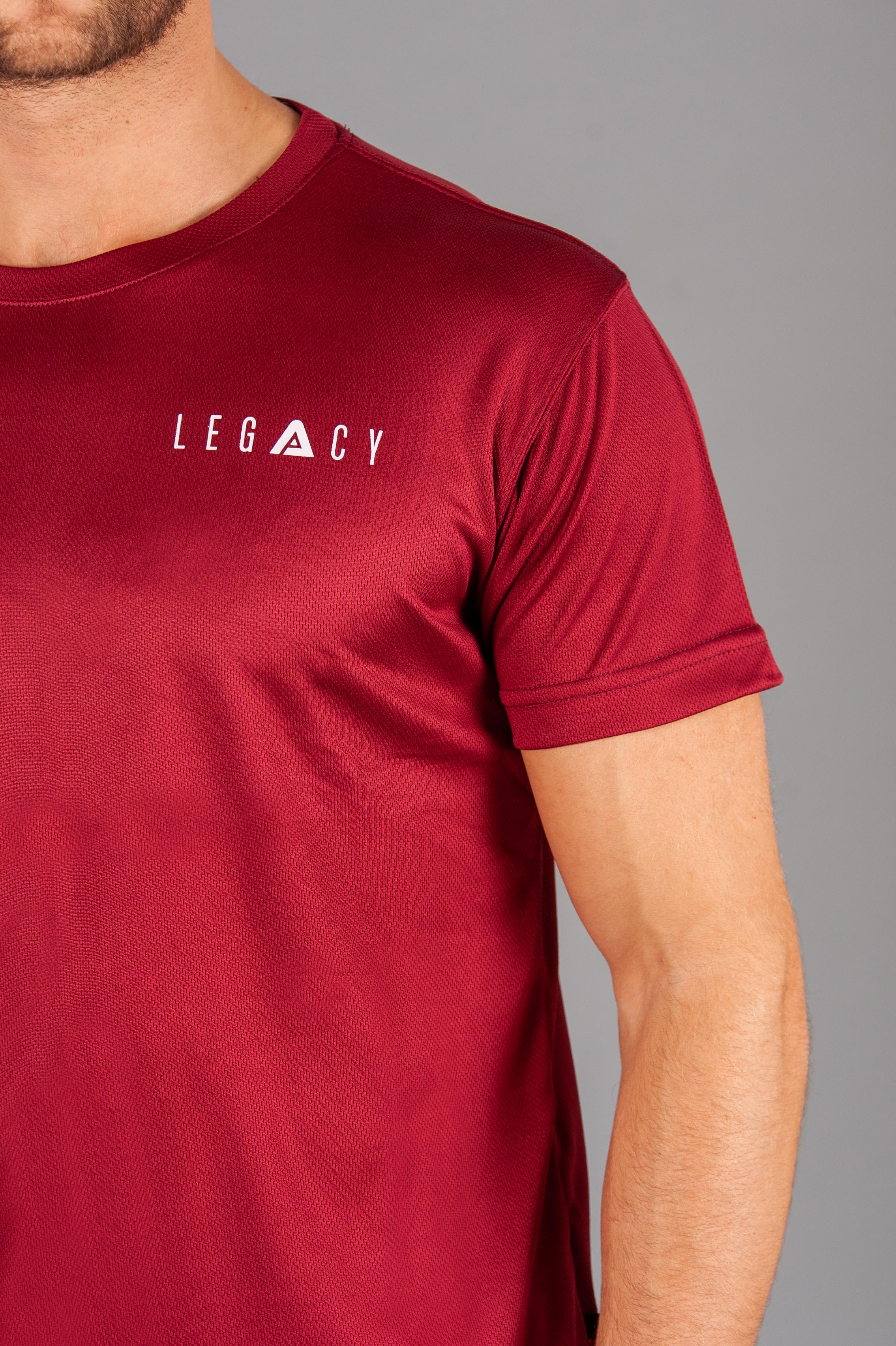Close up of white logo on men's burgundy moisture wicking crewneck t-shirt.