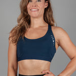 Women's navy sports bra with white Legacy logo on the side.