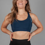 Women's navy sports bra with white Legacy logo on the side.