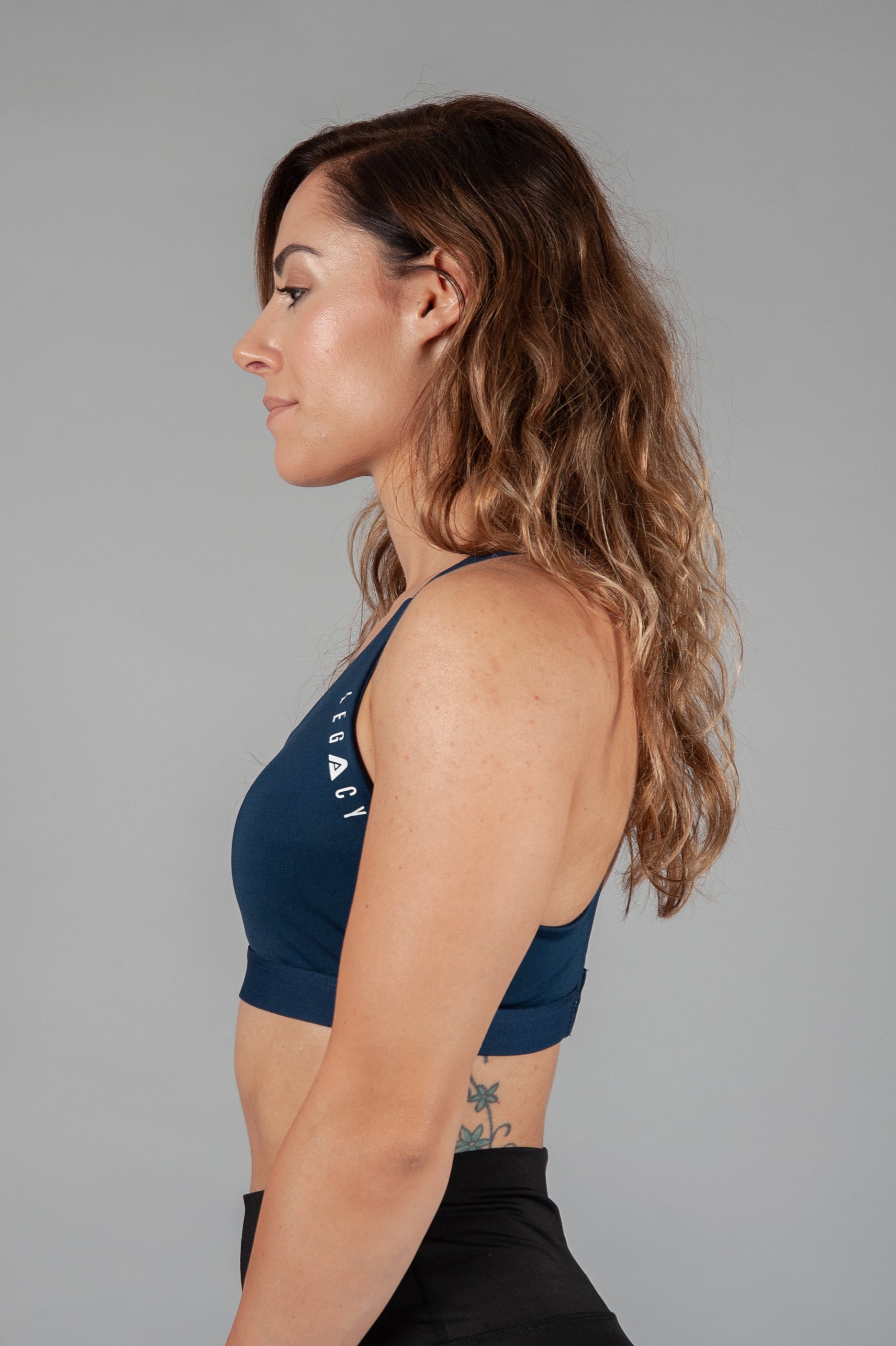 Women's navy sports bra with white Legacy logo on the side.