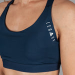 Women's navy sports bra with white Legacy logo on the side.