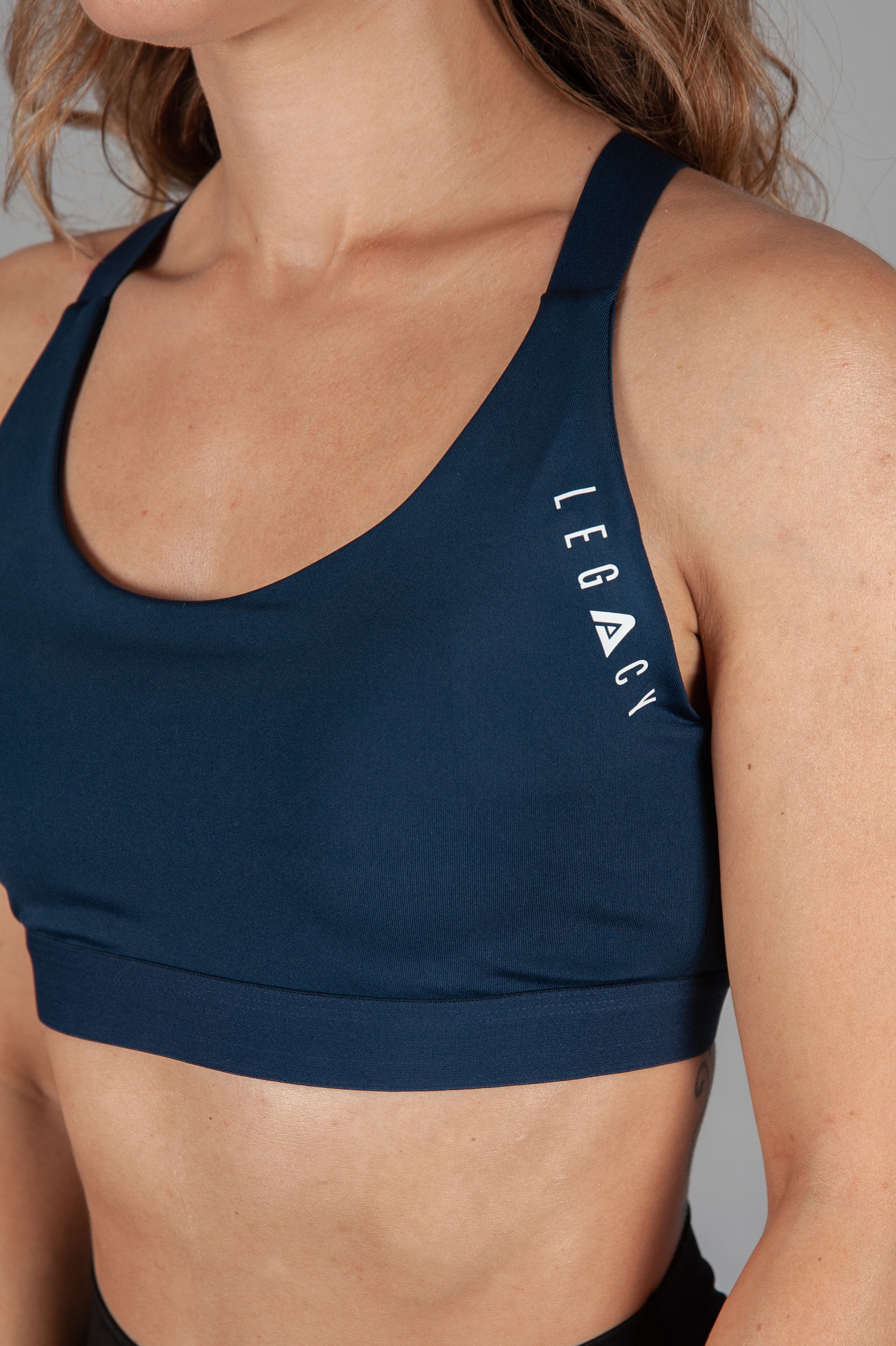 Women's navy sports bra with white Legacy logo on the side.