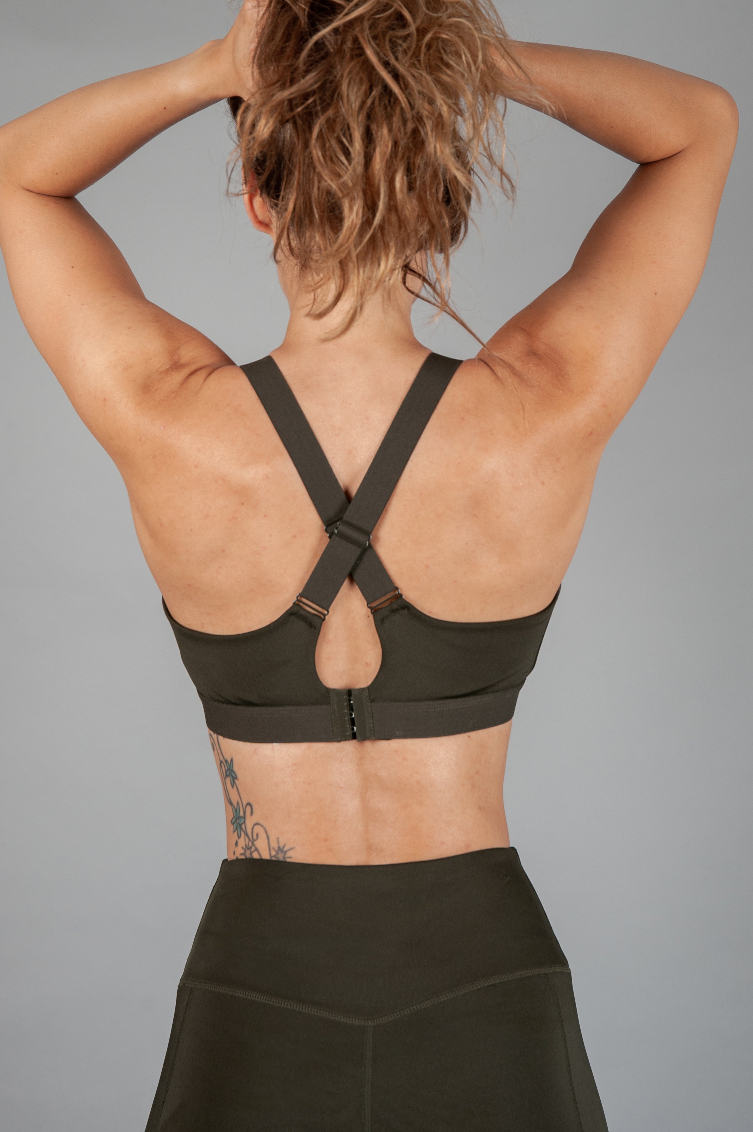 Women's olive sports bra with cross-over adjustable straps and clasp back.